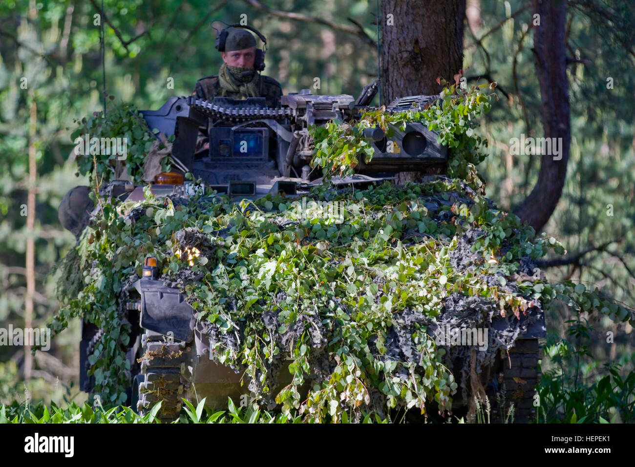 German Army Staff Sgt. Jonathan Lucke, a native of Stuttgart, assigned to 5th Company, Jager Battalion 292, sits in his camouflaged Wiesel A2 track vehicle and observes the surrounding area for enemy threats during the second day of multinational training at the Great Lithuanian Hetman Jonusas Radvila Training Regiment, in Rukla, Lithuania, June 11, 2015. The training is part of a larger exercise being conducted throughout the Baltic States called Saber Strike 2015. Saber Strike is a long-standing U.S. Army Europe-led cooperative training exercise. This year’s exercise objectives facilitate co Stock Photo