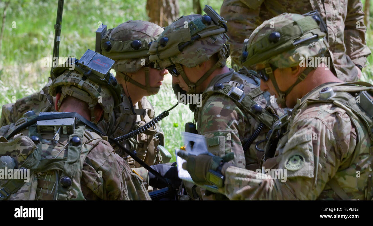 United States Army Capt. Bryan E. Adams, commander of Team Eagle, Task Force 2-7 Infantry, center, radios his position to higher headquarters during the second day of multinational training at the Great Lithuanian Hetman Jonusas Radvila Training Regiment, in Rukla, Lithuania, June 11, 2015. The training is part of a larger exercise being conducted throughout the Baltic States called Saber Strike 2015. Saber Strike is a long-standing U.S. Army Europe-led cooperative training exercise. This year’s exercise objectives facilitate cooperation between the U.S., Estonia, Latvia, Lithuania, and Poland Stock Photo