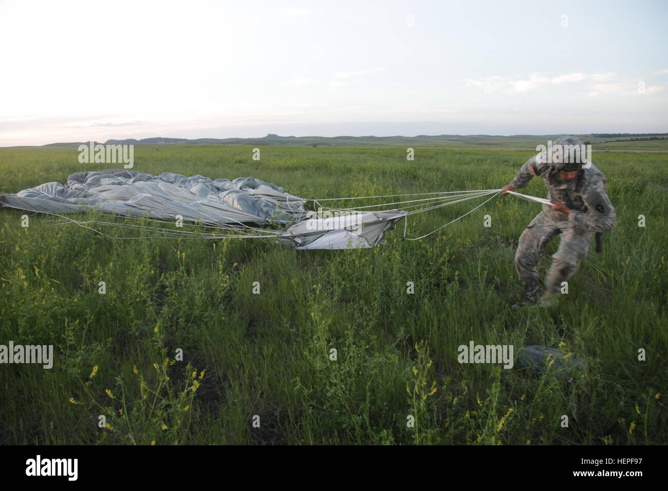 U.S. Army Spc. Clayton Weldon with the Forward Support Company, 1-143rd Airborne Infantry Regiment, Texas Army National Guard, gathers parachute after landing on Jonn Edmunds Drop Zone during the Golden Coyote training exercise, at Camp Guernsey, Guernsey, Wyo., June 15, 2015. Golden Coyote is a three phase, scenario-driven exercise conducted in the Black Hills of South Dakota and Wyoming. The exercise enables commanders to focus on mission essential task requirements, warrior tasks and drills. (U.S. Army photo by Spc. Tamara Cummings/Released) Golden Coyote 150614-A-FA208-045 Stock Photo