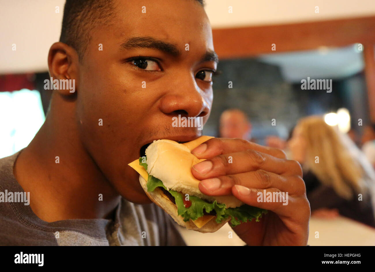 U.S. Army Pvt. Khalil Sinclair, assigned to 55th Signal Company (Combat Camera), eats a burger during a unit picnic at Burba Lake Cottage on Fort George G. Meade, Md., July 2, 2015. The unit held the picnic to celebrate the Independence Day holiday and build esprit de corps. (U.S. Army photo by Pfc. Brittany Dempsey/Released) 55 th Signal Company (Combat Camera) FRG Company Picnic 150702-A-IP716-310 Stock Photo