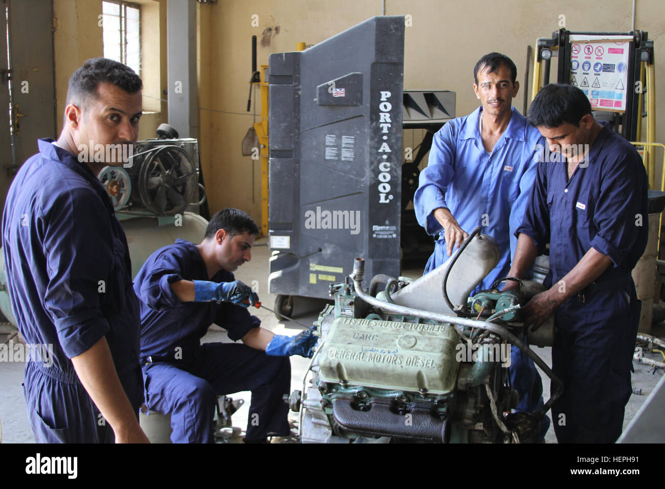 Iraqi security force mechanics rebuild an engine for an M113 Armored Personnel Carrier at the tracked vehicle repair facility on Camp Taji, Iraq, July 11, 2015. A team of tracked vehicle mechanics from the U.S. Army’s 3rd Brigade Combat Team, 4th Mechanized Infantry Division, serve as a maintenance advise and assist team to the ISF mechanics, serving the Iraqi logistics depot, in support of Combined Joint Task Force – Operation Inherent Resolve. (Photo by Capt. A. Sean Taylor/Released) Maintenance A& A; team builds engines, relationships 150711-A-NL725-002 Stock Photo