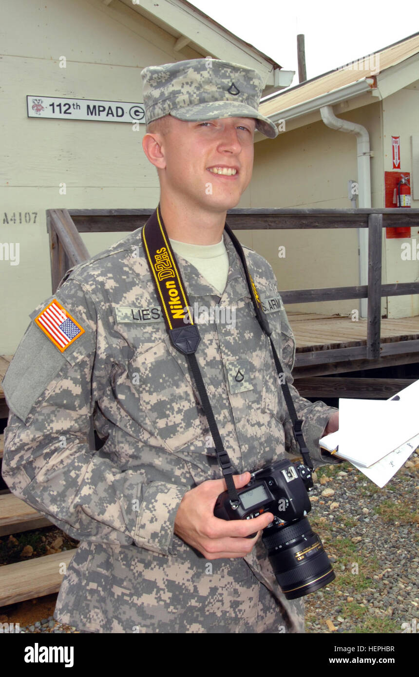 GUANTANAMO BAY, Cuba - Pfc. Eric Liesse, a photojournalist with the 112th Mobile Public Affairs Detachment, stands with the tools of his trade, a Nikon D2H camera, a notepad and pen. Liesse was recently named Trooper of the Quarter for the Joint Task Force Guantanamo Bay. JTF Guantanamo conducts safe and humane care and custody of detained enemy combatants. The JTF conducts interrogation operations to collect strategic intelligence in support of the Global War on Terror and supports law enforcement and war crimes investigations. JTF Guantanamo is committed to the safety and security of America Stock Photo