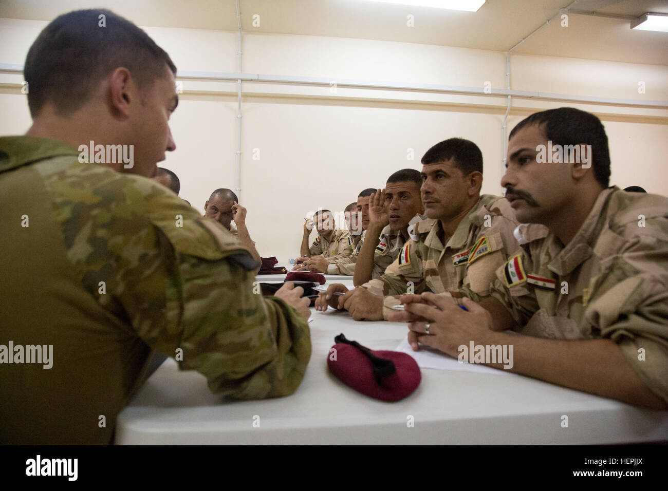 An Australian soldier assigned to Task Group Taji speaks to a group of Iraqi soldiers attending the noncommissioned officer academy at Camp Taji, Iraq, Aug. 22, 2015. Task Group Taji spearheaded the academy concept in order to teach Iraqi NCOs how to train and care for their soldiers in different situations. Through professional development with the Iraqi NCOs, Combined Joint Task Force – Operation Inherent Resolve is empowering the Iraqi security forces in the fight against the Islamic State of Iraq and the Levant. (U.S. Army photo by Spc. Paris Maxey/Released) Iraqis attend NCO academy 15082 Stock Photo