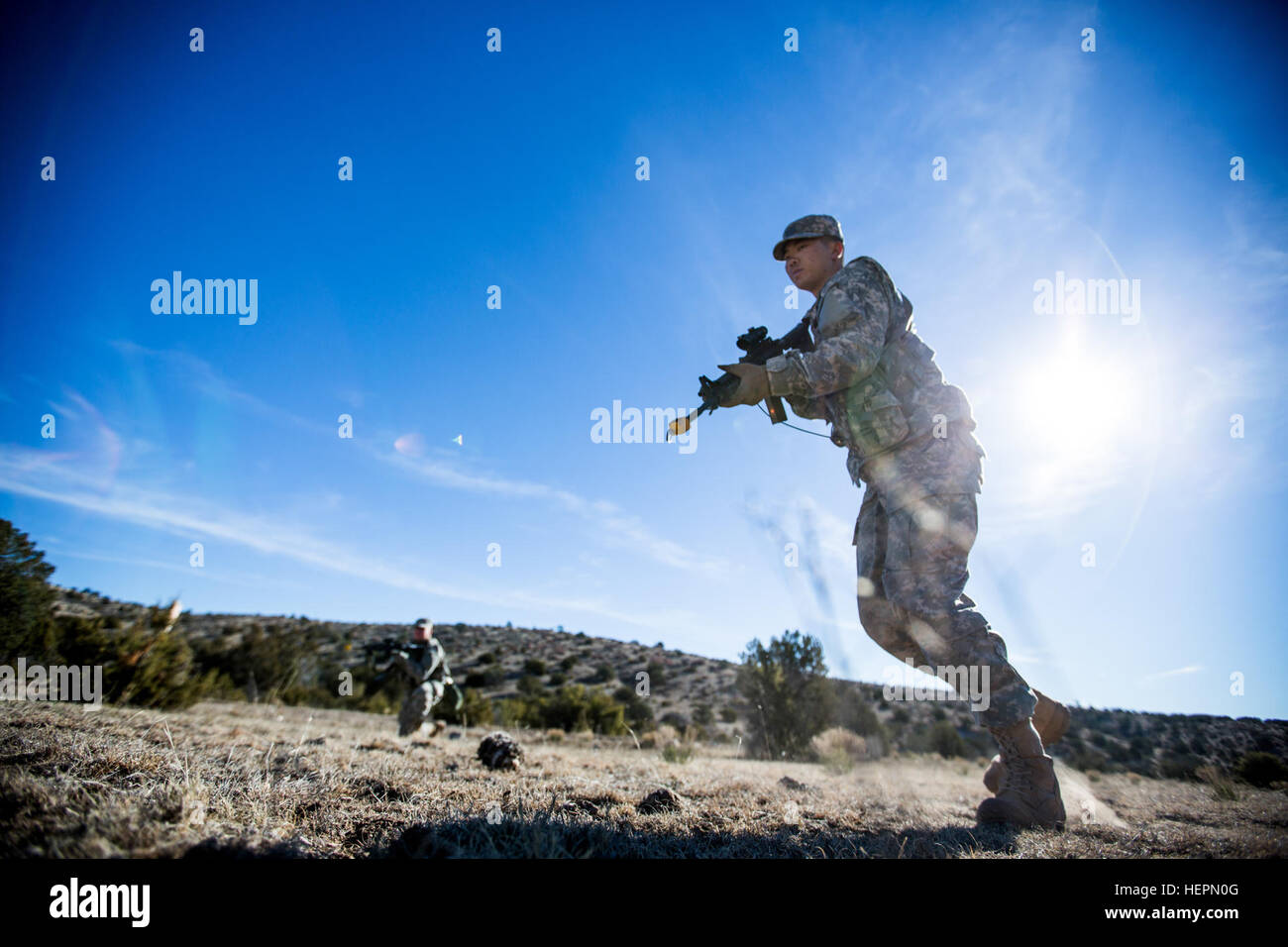 A Desert Warrior student launches across a field  during the battle drills lane as part of the Desert Warrior school, Iron Training Detachment, 1st Armored Division at Fort Bliss, Texas, Jan. 22, 2016. Desert Warrior, the newest squad based leadership class in the Army, teaches soldiers how to survive and fight in a desert environment. The 17-day class is the first desert specific Army school since the desert phase of Ranger School was discontinued in 1995. (U.S. Army photo by Staff Sgt. Marcus Fichtl) Desert Warrior battle drills 160122-A-TW035-006 Stock Photo