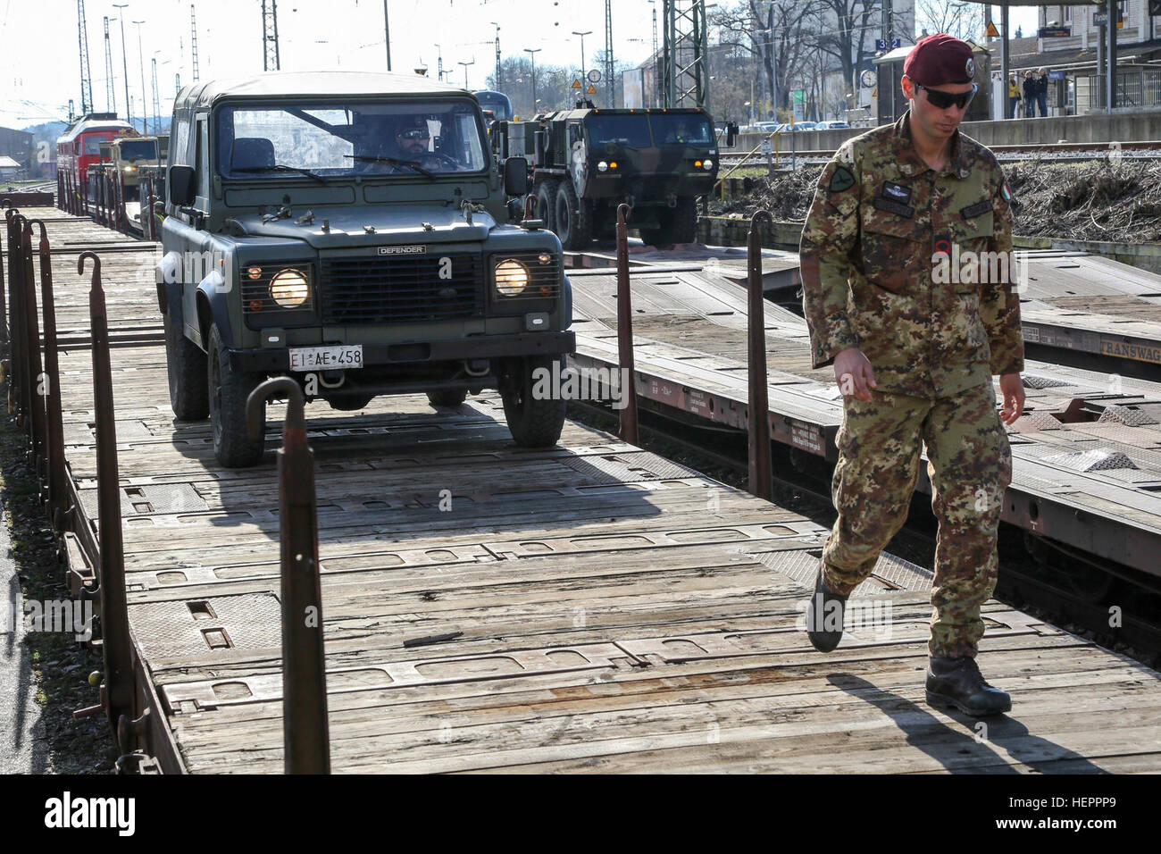 An Italian soldier of Folgore Parachute Brigade ground guides a Land Rover Defender 90 off rail cars in preparation for a convoy during exercise Saber Junction 16 at the U.S. Army’s Joint Multinational Readiness Center (JMRC) in Hohenfels, Germany, April 7, 2016. Saber Junction 16 is the U.S. Army Europe’s 173rd Airborne Brigade’s combat training center certification exercise, taking place at the JMRC in Hohenfels, Germany, Mar. 31-Apr. 24, 2016.  The exercise is designed to evaluate the readiness of the Army’s Europe-based combat brigades to conduct unified land operations and promote interop Stock Photo