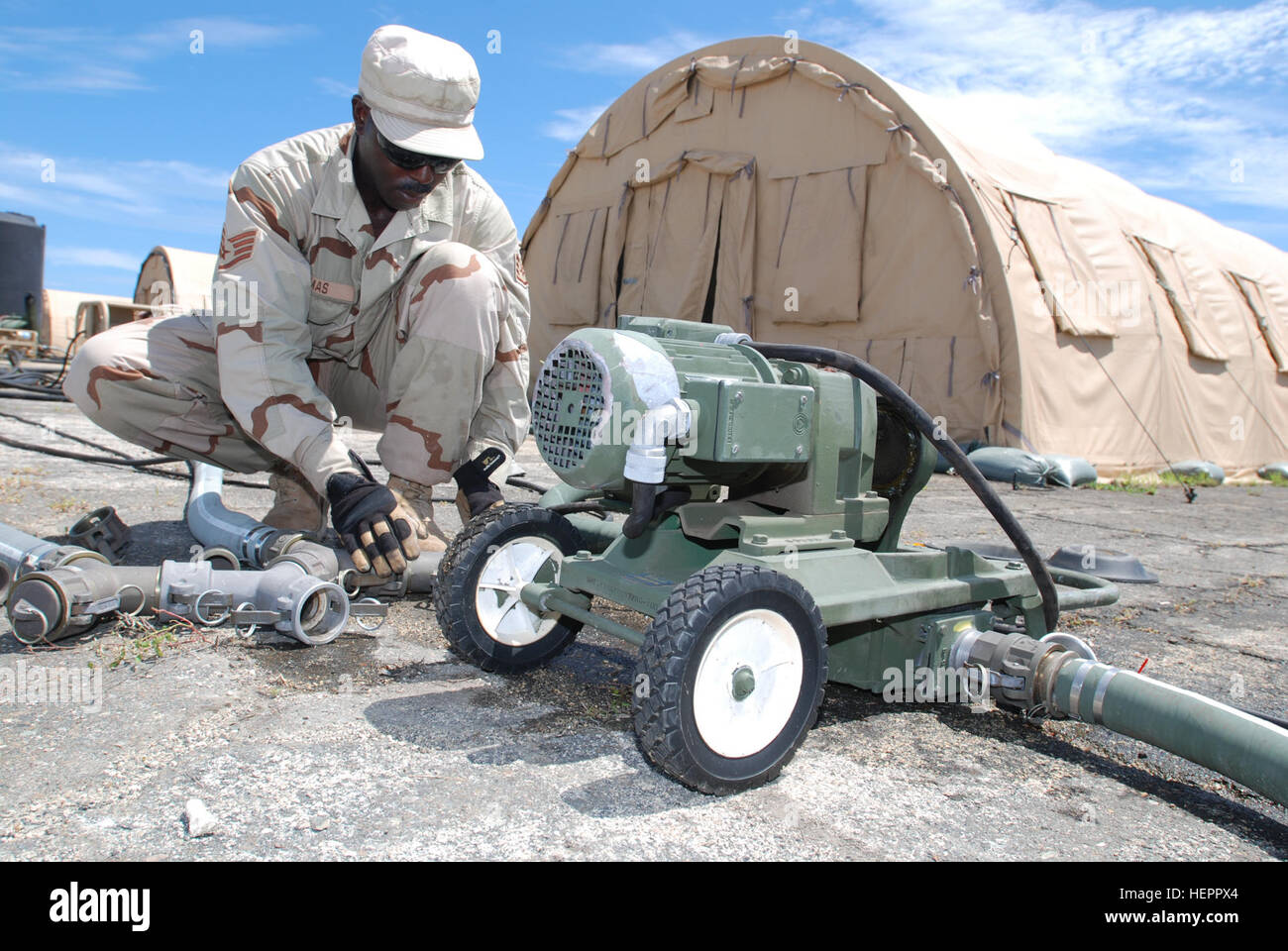 Air Force Staff Sgt. Robert Thomas, an engineer with the 474th Prime Base Engineer Emergency Force, repairs a hole in the diaphragm of a pump at Joint Task Force Guantanamo's Camp Justice, Sept. 19, 2008. The pump provides the force by which water is moved from shower facilities at the Camp to a waste water tank, also on the premises. JTF Guantanamo conducts safe, humane, legal and transparent care and custody of detained enemy combatants, including those convicted by military commission and those ordered released. JTF Guantanamo conducts intelligence collection, analysis and dissemination for Stock Photo