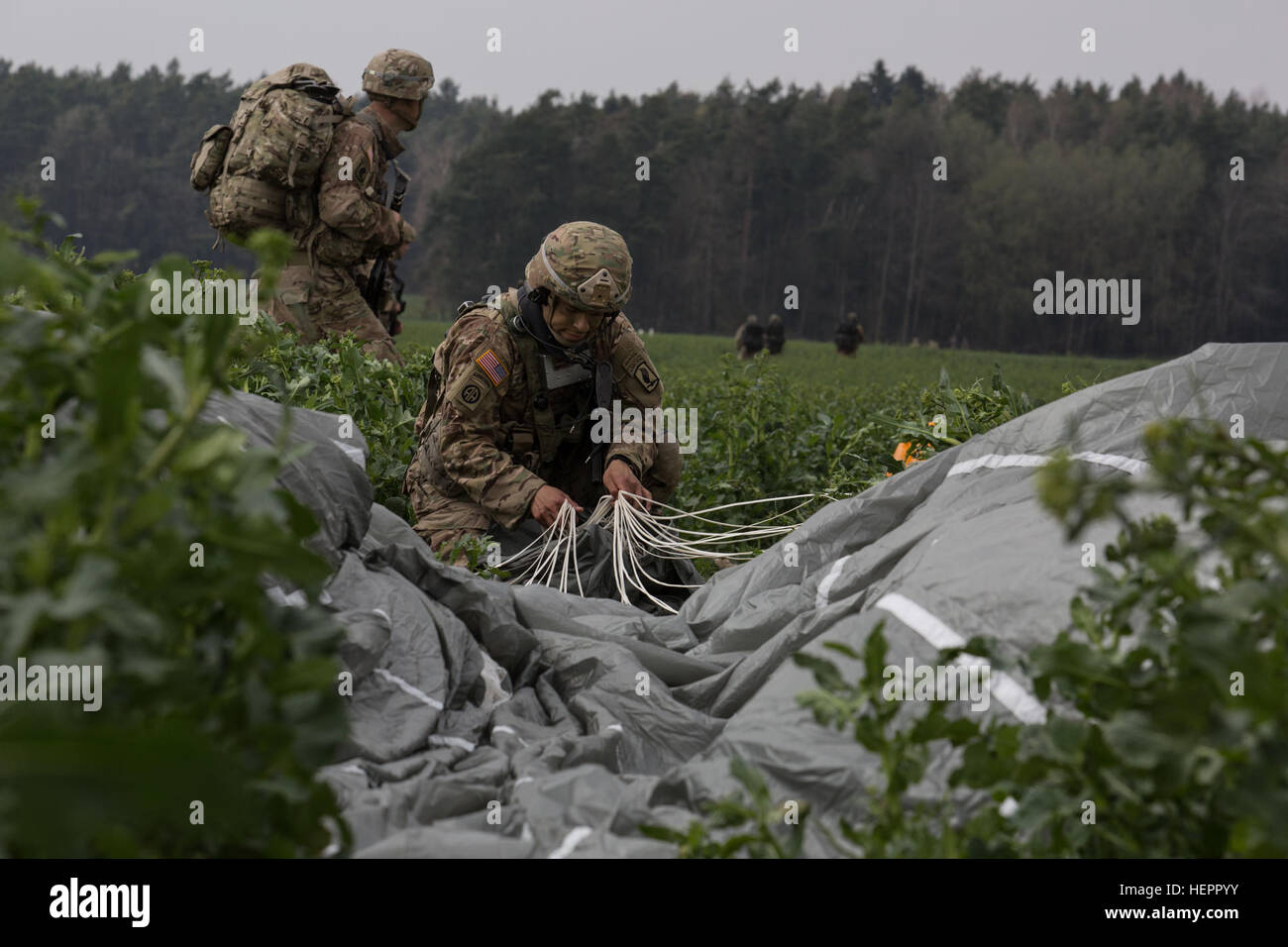 A U.S. Soldier of the 173rd Airborne Brigade jump gathers his parachute while conducting an airborne operation during exercise Saber Junction 16 at the German Maneuver Rights Area outside Hohenfels, Germany, April 12, 2016. Saber Junction 16 is the U.S. Army Europe’s 173rd Airborne Brigade’s combat training center certification exercise, taking place at the JMRC in Hohenfels, Germany, Mar. 31-Apr. 24, 2016.  The exercise is designed to evaluate the readiness of the Army’s Europe-based combat brigades to conduct unified land operations and promote interoperability in a joint, multinational envi Stock Photo