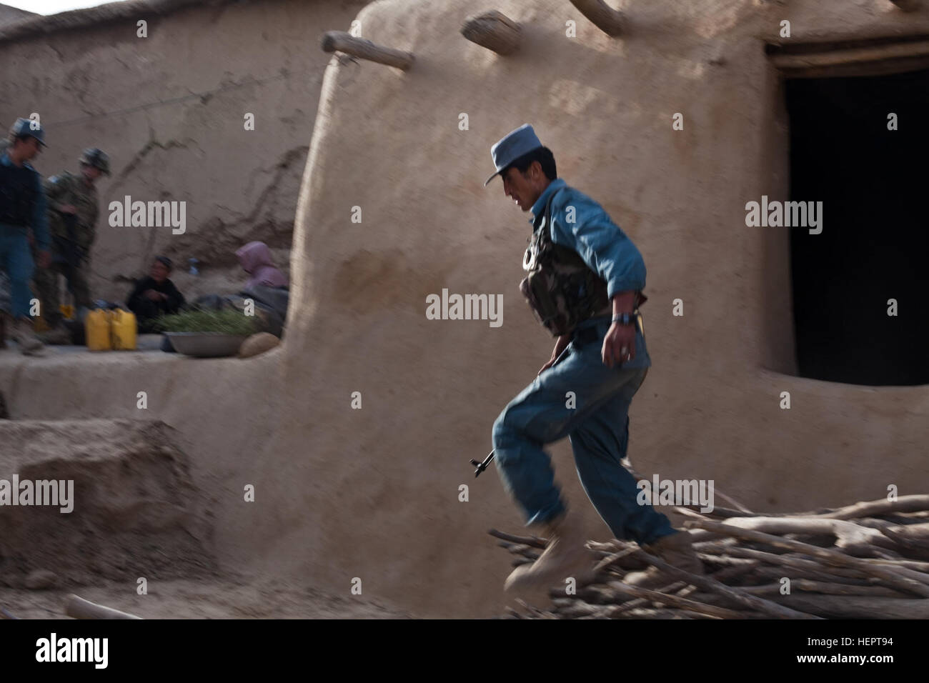 A Kalat District Afghan National Police officer jumps off a stack of water during a mission with U.S. Army soldiers assigned to Charlie Company, 1st Battalion, 24th Infantry Regiment, 2nd Brigade, 25th Infantry Division, to clear the village of Nawrak, Afghanistan, June 26, 2011. The Afghan National Police actively search the houses in the village while the Afghan National Army and U.S. Army soldiers provide security. Kalat District ANP patrol in Nawrak 110626-A-UJ825-049 Stock Photo