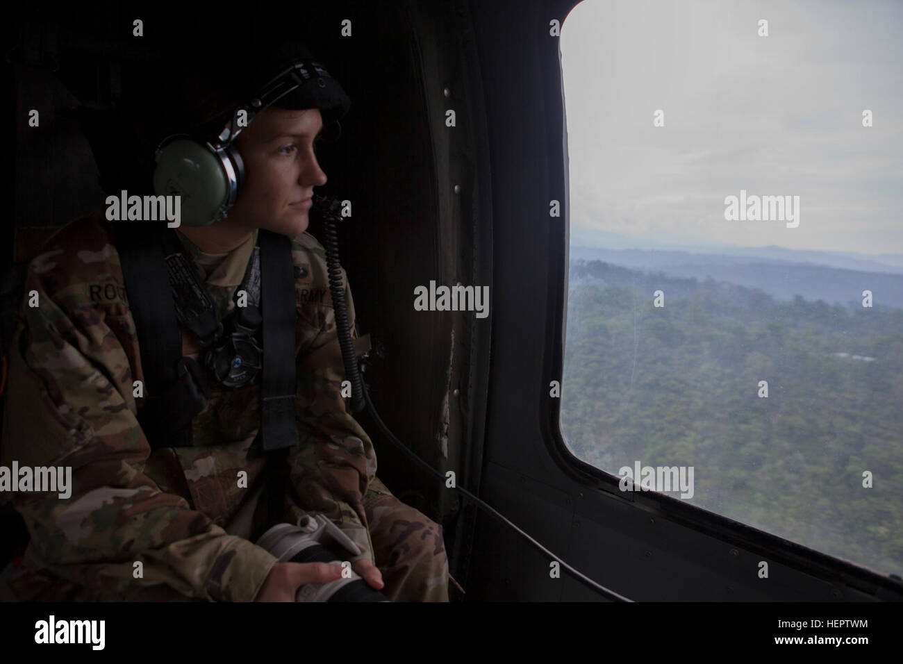 U.S. Army Spc. Kristen Root of the 982nd Combat Camera unit (Airborne), East Point, Georgia analyzes out of the window of a UH-60 Black Hawk helicopter to decide her next shot she will take with her camera in San Marcos, Guatemala, May 27, 2016.  Task Force Red Wolf and Army South conducts Humanitarian Civil Assistance Training to include tactical level construction projects and Medical Readiness Training Exercises providing medical access and building schools in Guatemala with the Guatemalan Government and non-government agencies from 05MAR16 to 18JUN16 in order to improve the mission readine Stock Photo