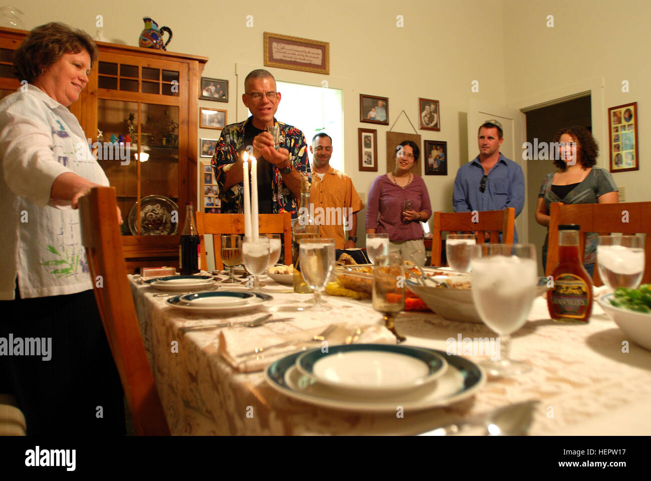 GUANTANAMO BAY, Cuba – Navy Chaplain Rabbi Seth Phillips prays over the Kos L’Kiddush, or Kiddush cup, before a Shabbat dinner at the naval station residence of Jeff and Kathy Einhorn Friday, Sept. 26, 2008. Kathy Einhorn is seen at left. Phillips, a chaplain stationed at Naples, Italy, is visiting Guantanamo Bay for a week to help celebrate Rosh Hashanah, the Jewish new year which began Sept. 29. Shabbat is a Friday night dinner, the main meal of the week in many Jewish households, and begins after sundown to welcome the Jewish Sabbath. JTF Guantanamo conducts safe, humane, legal and transpar Stock Photo