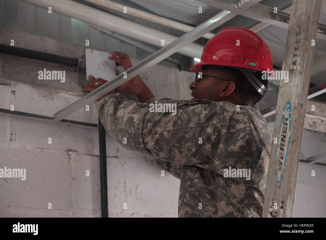 U.S. Army Spc. Shemar Moss, assigned to the 1022nd Engineering Battalion, Arizona National Guard, attaches a cover to an electrical box inside a clinic in La Blanca, Guatemala, June 6, 2016. Task Force Red Wolf and Army South conducts Humanitarian Civil Assistance Training to include tactical level construction projects and Medical Readiness Training Exercises providing medical access and building schools in Guatemala with the Guatemalan Government and non-government agencies from 05MAR16 to 18JUN16 in order to improve the mission readiness of US Forces and to provide a lasting benefit to the  Stock Photo