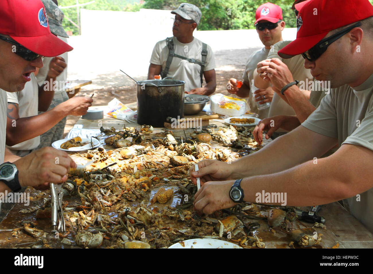 U.S. airmen and Soldiers feast on a crab boil cooked by residents of the village of La Guazara, Dominican Republic, as part of Beyond the Horizon 2014, a three-month multinational humanitarian exercise, June 7, 2014. The airmen in the red ball caps are part of the Air National Guard's 200th and 210th RED HORSE (Rapid Engineer Deployed Heavy Operational Repair Squadron Engineers) Squadrons from Ohio and New Mexico and are on a two-week rotation to finish up construction on a school in the village. Beyond the Horizon 2014 140607-A-JF456-128 Stock Photo