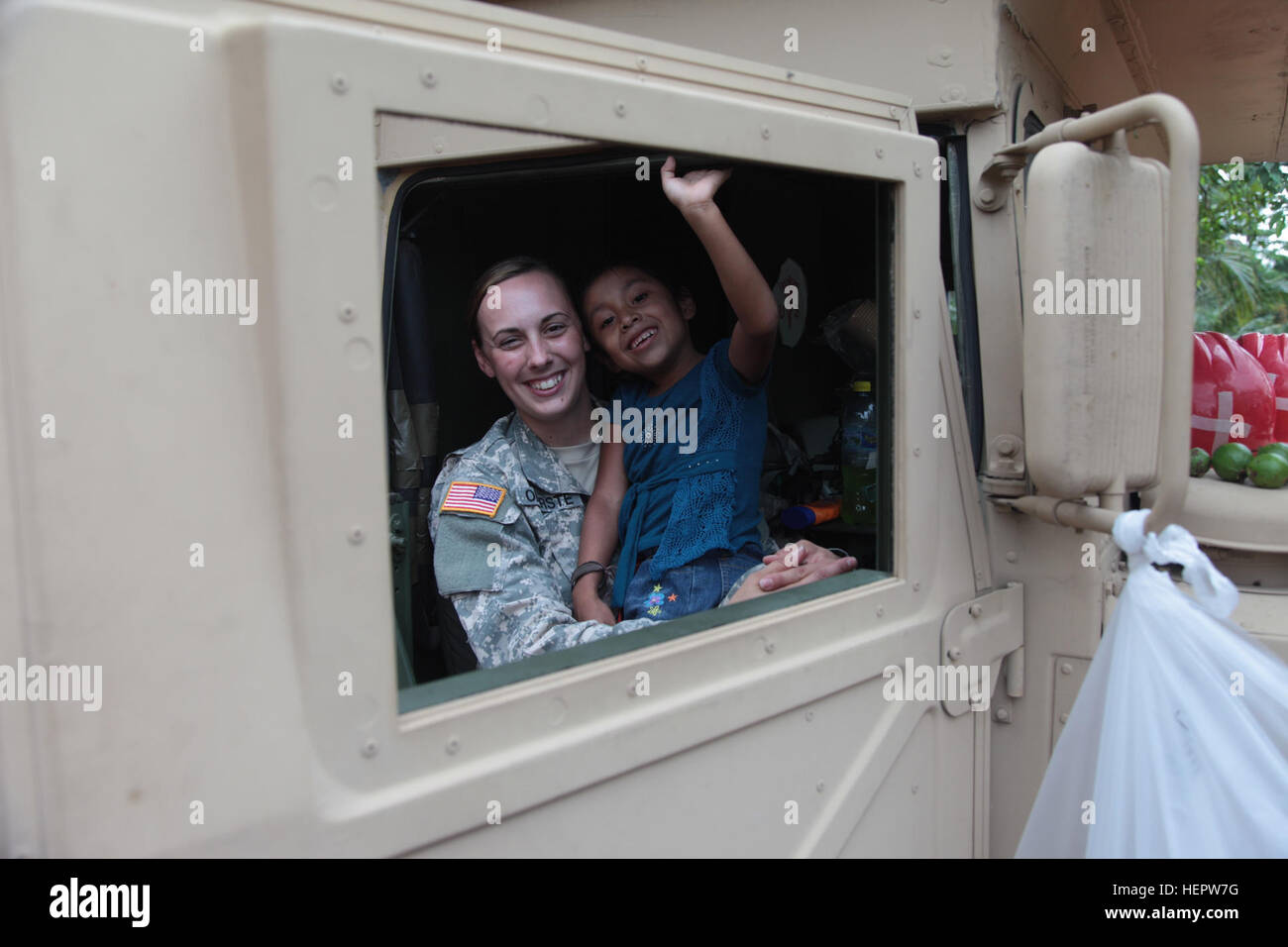 U.S. Army Spc. Elisha Oberste assigned to the 296th Medical Company Arkansas National Guard, holds a Guatemalan child in her lap inside a HMMV at the Catarina construction site, Guatemala, June 8, 2016. Task Force Red Wolf and Army South conducts Humanitarian Civil Assistance Training to include tactical level construction projects and Medical Readiness Training Exercises providing medical access and building schools in Guatemala with the Guatemalan Government and non-government agencies from 05MAR16 to 18JUN16 in order to improve the mission readiness of US forces and to provide a lasting ben Stock Photo