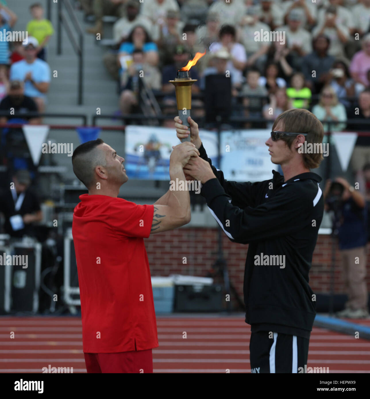 U.S. Marine Gunnery Sergeant Andrew Cordova, of Clovis, New Mexico, hands off the torch to U.S. Army Veteran Spc. Terry Cartwright of Safford, Ariz, during the 2016 Department of Defense Warrior Games opening ceremony, in Shea Stadium, at the United States Military Academy, at West Point, New York, June 15. (U.S. Army Photo by Pfc. Stefan English/Released) DoD Warrior Games 2016 160615-A-QP791-512 Stock Photo