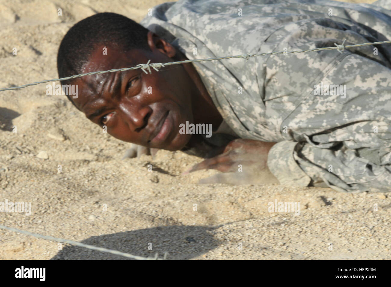 A military police officer navigates a low crawl under barbed wire at ...