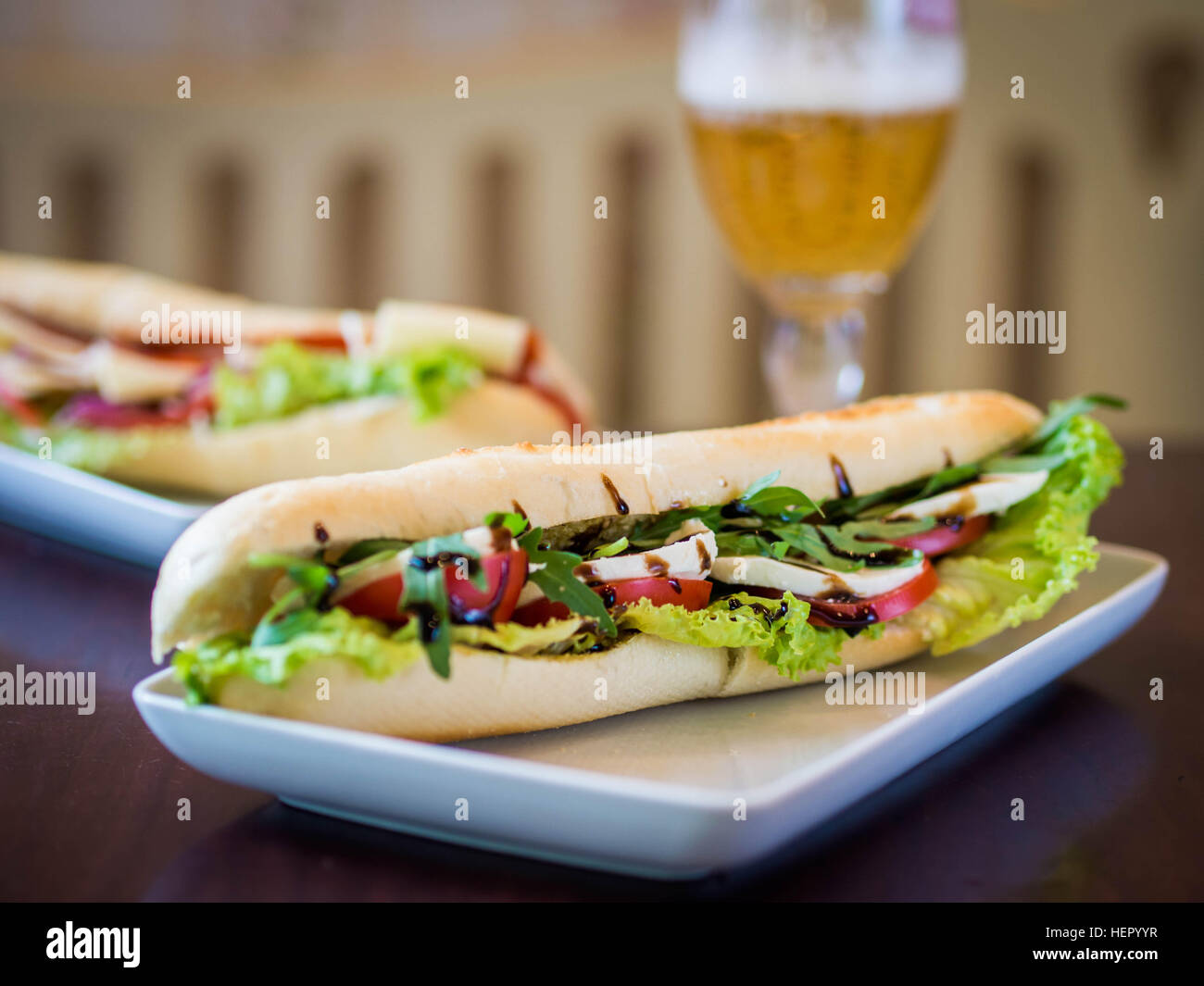 Mozzarella, tomato and balsamic vinegar baguette with glass of beer Stock Photo