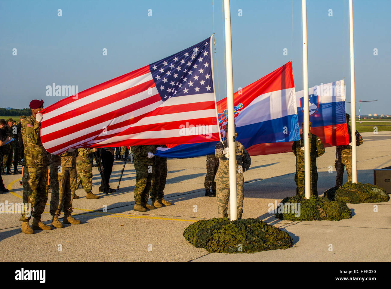 Soldiers from the United States, Croatia, and Slovenia raise the flags during the Immediate Response 16 Opening Ceremony. Immediate Response 16 is a multinational, brigade-level command post exercise utilizing computer-assisted simulations and field training exercises spanning two countries, Croatia and Slovenia. The exercises and simulations are built upon a decisive action based scenario and are designed to enhance regional stability, strengthen Allied and partner nation capacity, and improve interoperability among partner nations. The exercise will occur Sept. 9-23, 2016, and will include m Stock Photo