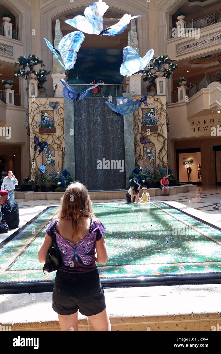 Woman with butterfly shirt watching glass butterflies at the Palazzo, Las Vegas, USA Stock Photo