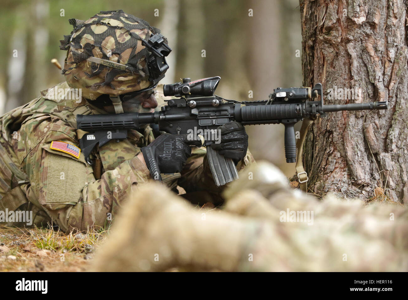 U.S. Army Sgt. Caleb Scanlan, Paratrooper, Company D, 2nd Battalion, 503rd Infantry Regiment, 173rd Airborne Brigade, takes cover behind a tree while firing an M4 5.56mm Carbine Assault Rifle while participating in a dismounted foot patrol during the unit's cumulative fire training event at Wedrzyn, Poland, Nov. 30, 2016. This was the culminating training event using all tactical assets in conjunction with one another while closing out the unit’s rotation in Poland and its continued support of Operation Atlantic Resolve and its NATO Allies. (U.S. Army photo by Sgt. William A. Tanner) 173rd Air Stock Photo