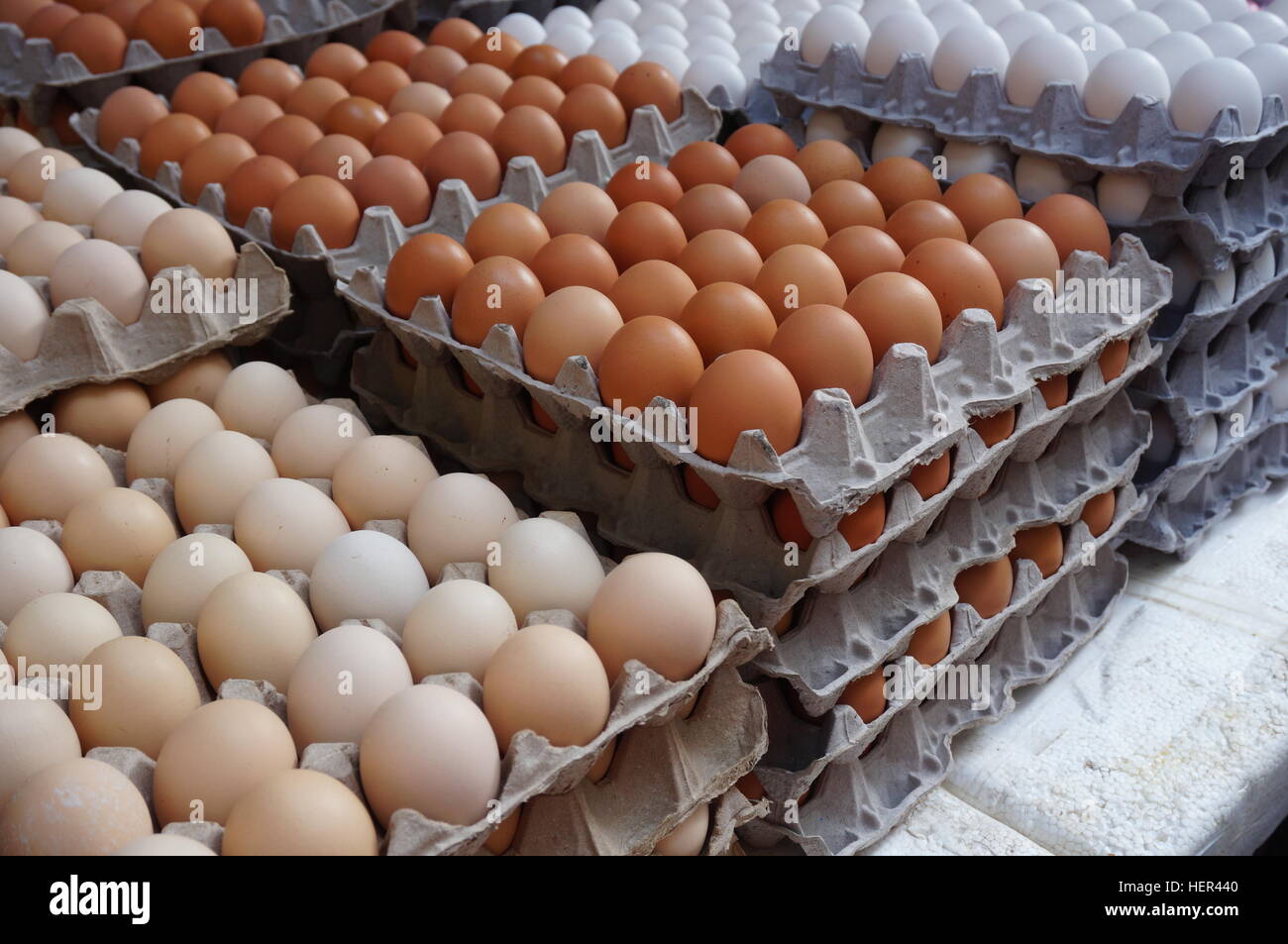 Giant cardboard crates of fresh white, yellow and brown eggs at the market Stock Photo