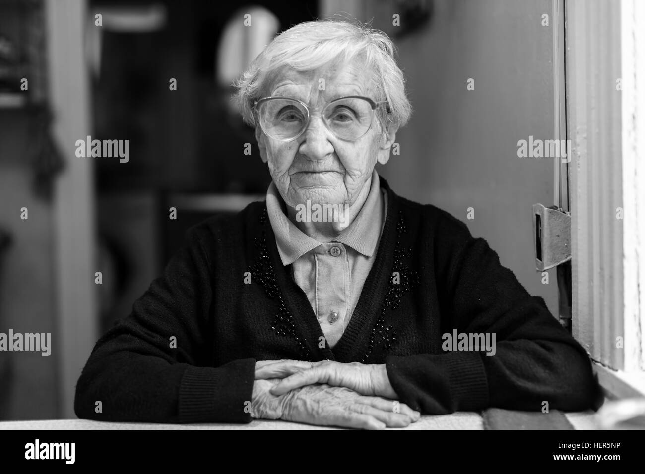 Old woman in glasses sitting in the house. Stock Photo
