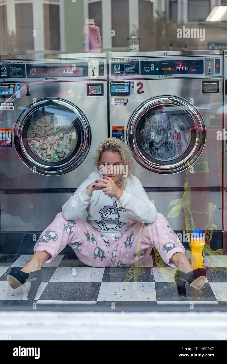 Frau sitzt vor Waschmaschine in einem Waschsalon in San Francisco Stock Photo