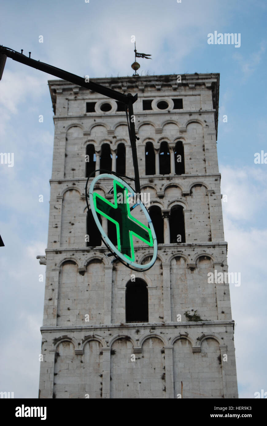 Kirchturm in der Altstadt von Lucca mit dem typischen grÃ¼nen Leuchtstoff-Kreuz fÃ¼r Apotheken in Italien im Vordergrund Stock Photo