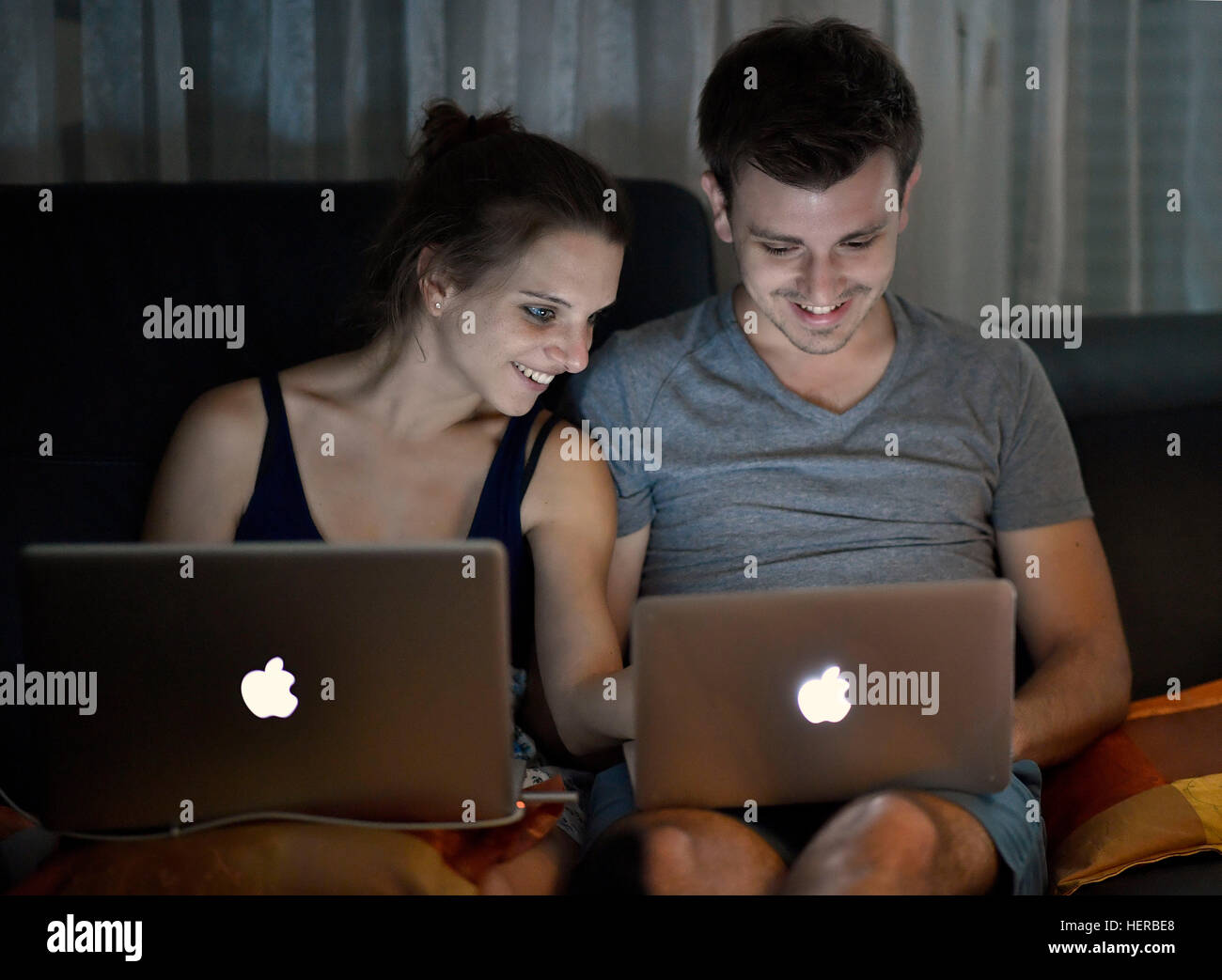 Junges Paar sitzt auf Sofa mit Laptop auf SchoÃŸ Stock Photo