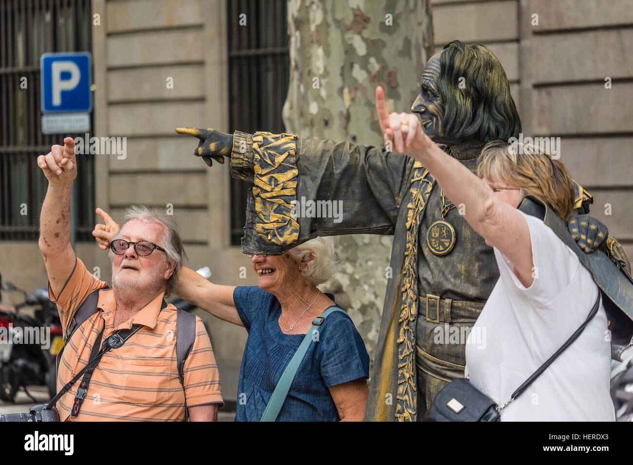 Three tourists having fun while pointing in the air with a street performer in on Las Ramblas, Barcelona, Spain. Stock Photo