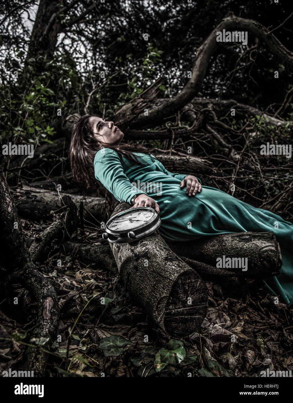 Girl with a green dress in a park holding clock Stock Photo - Alamy