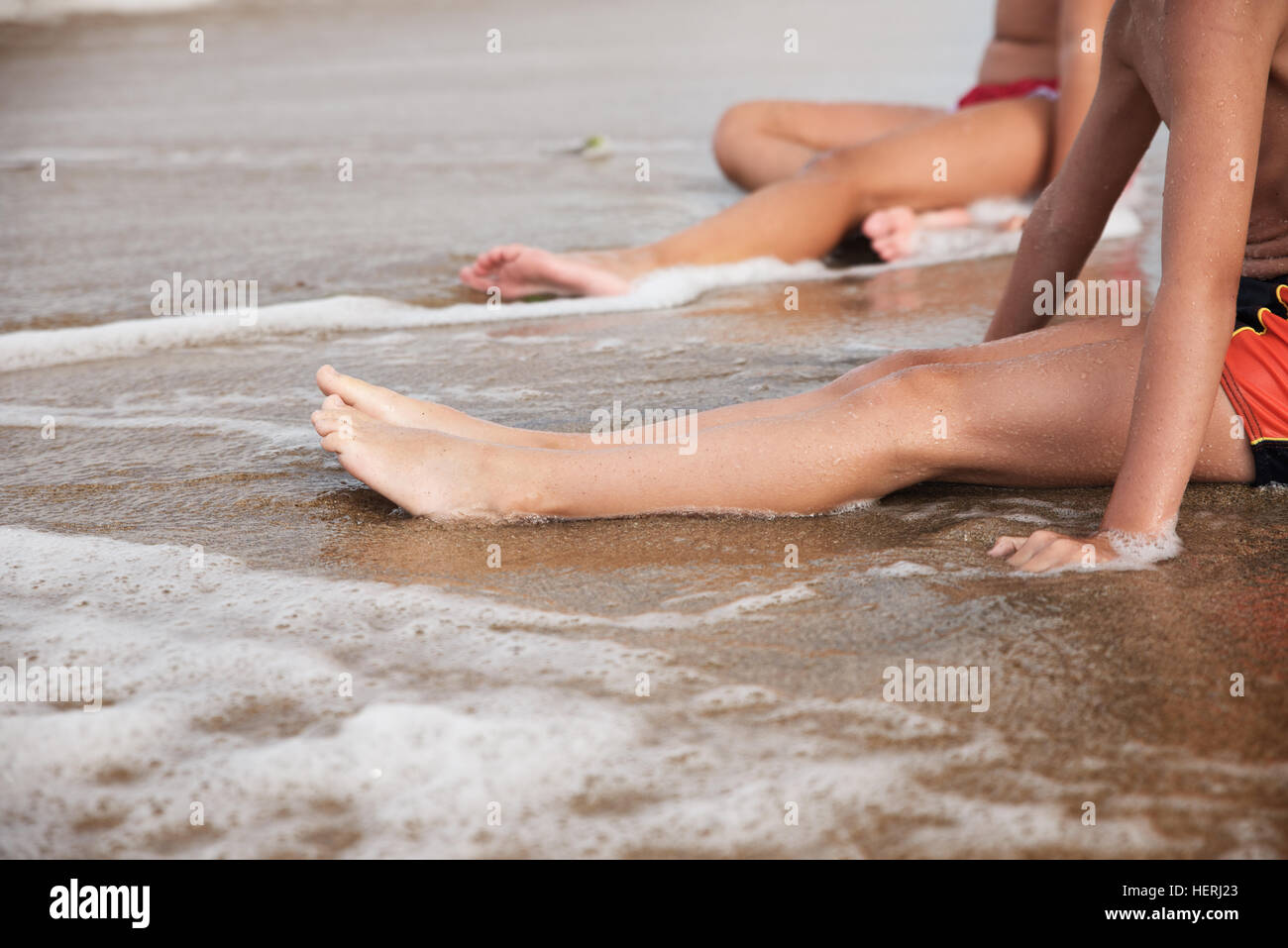 Close-up of a boy and girl sitting in surf on the beach Stock Photo