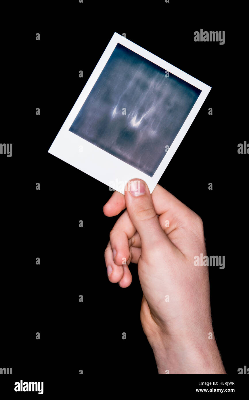 A hand holding an undeveloped polaroid photograph Stock Photo - Alamy