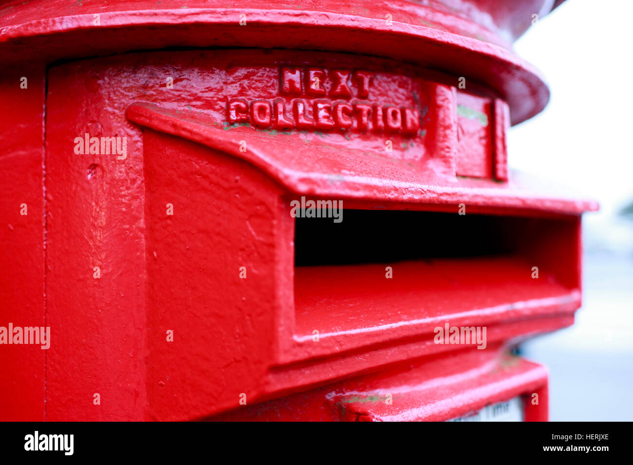 Cloe up of  a red painted UK post box with a large black jhole for posting letters into. Stock Photo