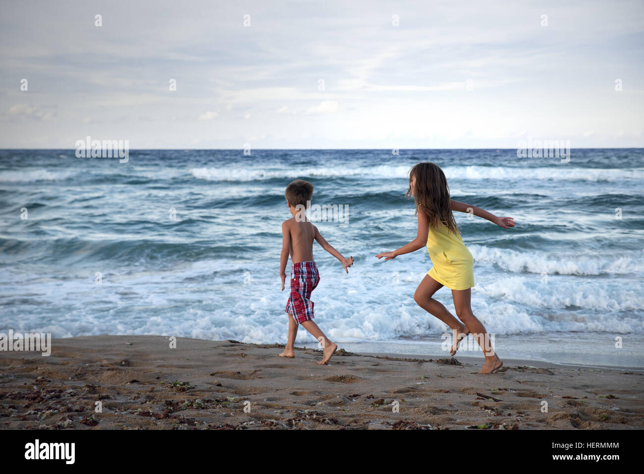 Boy and girl running along beach Stock Photo
