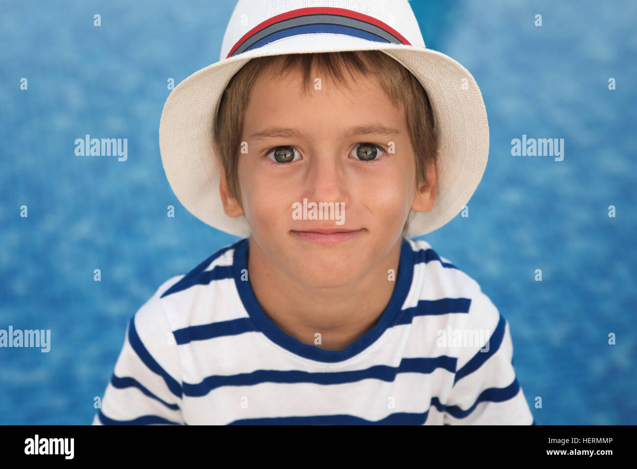 Portrait of a smiling boy by a pool wearing a summer hat Stock Photo