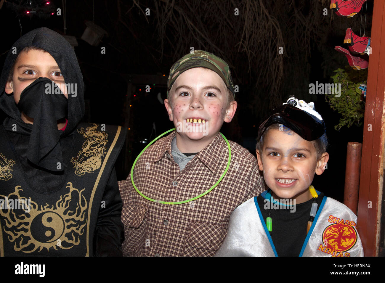 Three costumed boys in Halloween masked oriental Yin Yang & country bumpkin outfits trick or treating. St Paul Minnesota MN USA Stock Photo