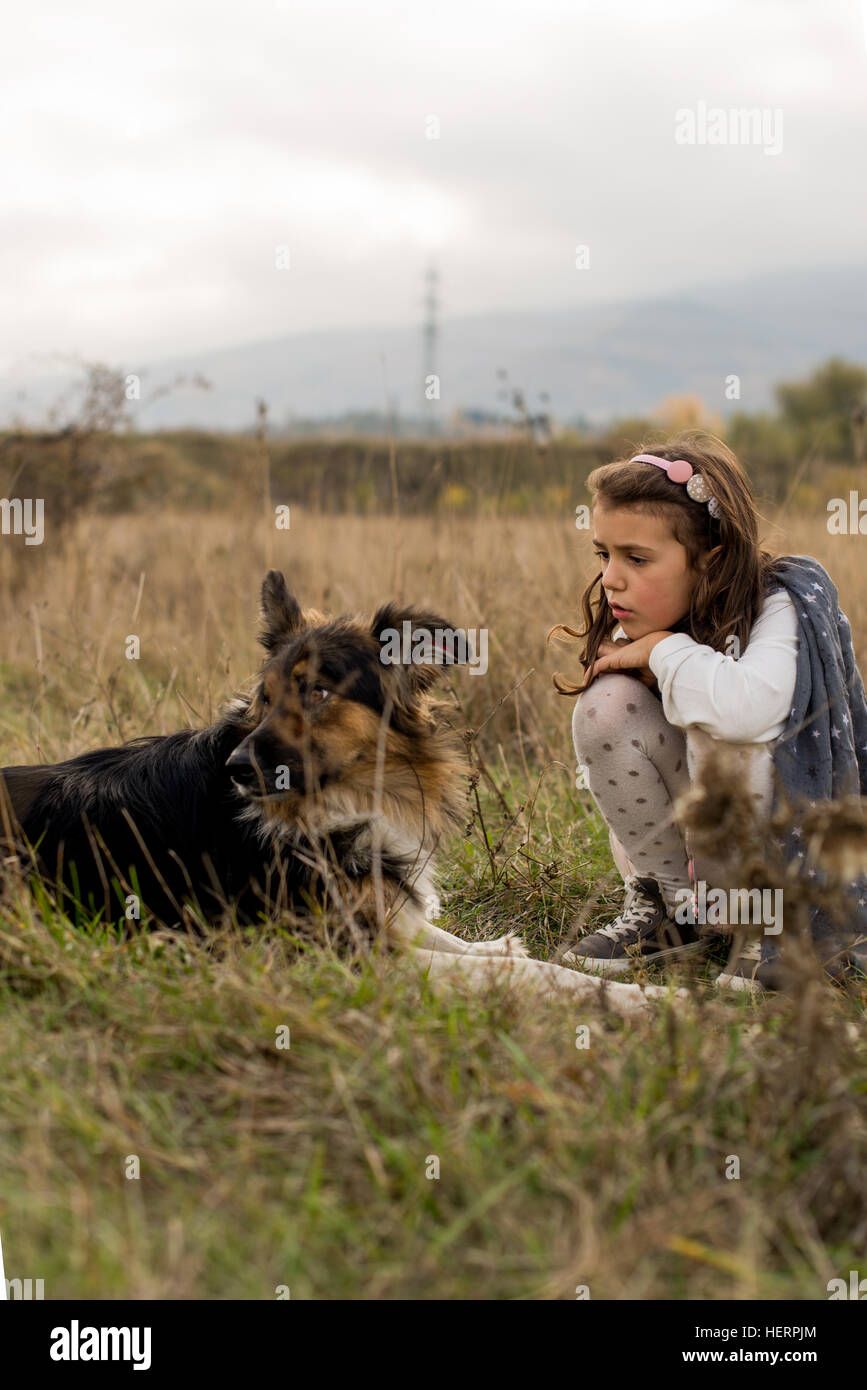 Girl sitting in a field with her dog Stock Photo