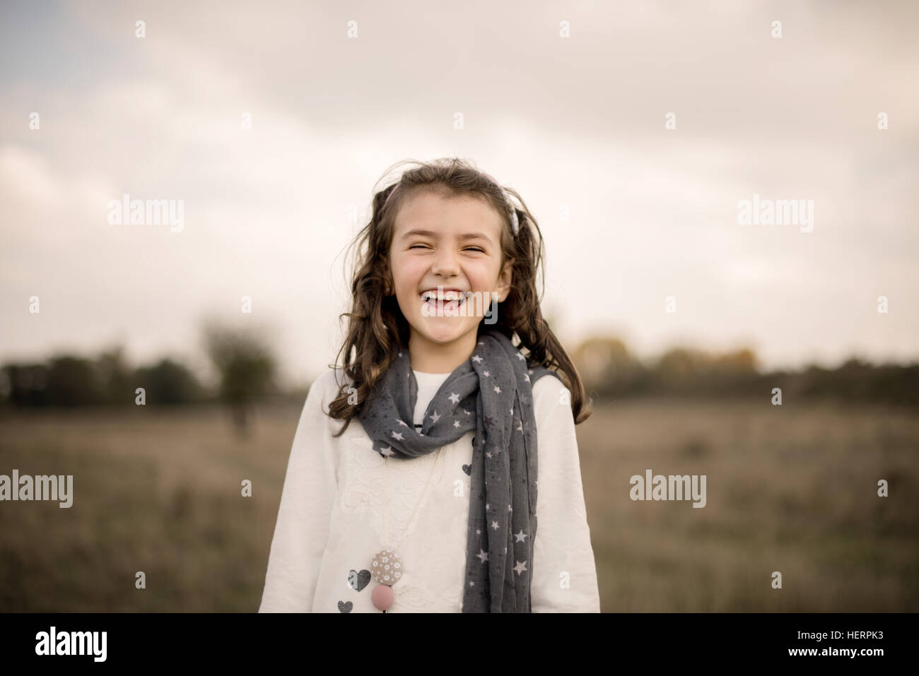Portrait of a girl standing in a field laughing Stock Photo