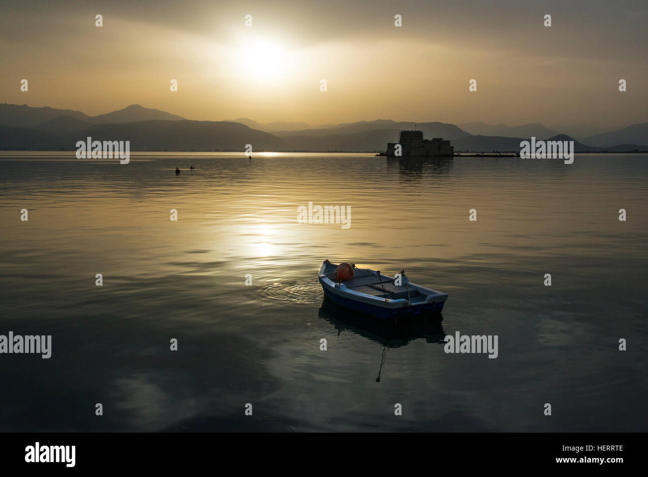 Approaching sunset over Argolic Gulf, Nafplion, Greece with rowboat and island on the sea. Stock Photo