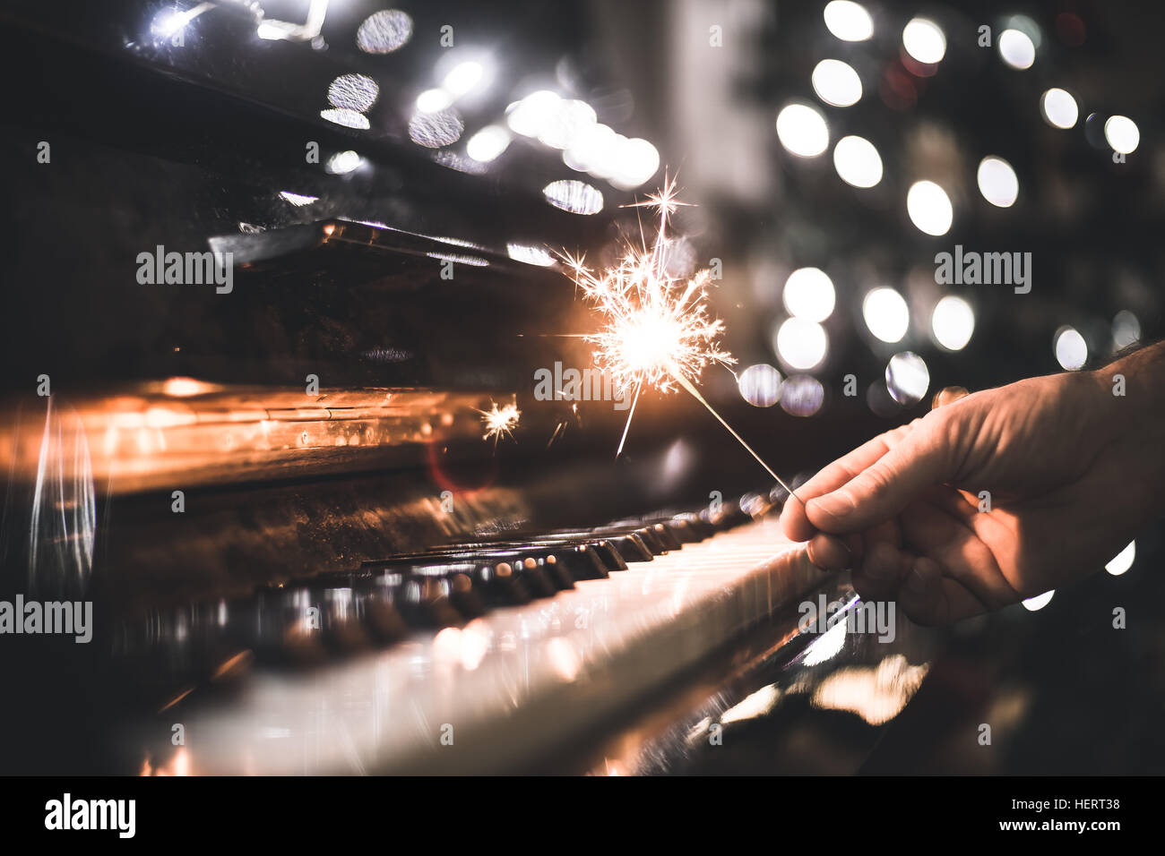 hand holding a sparkler over a piano Stock Photo