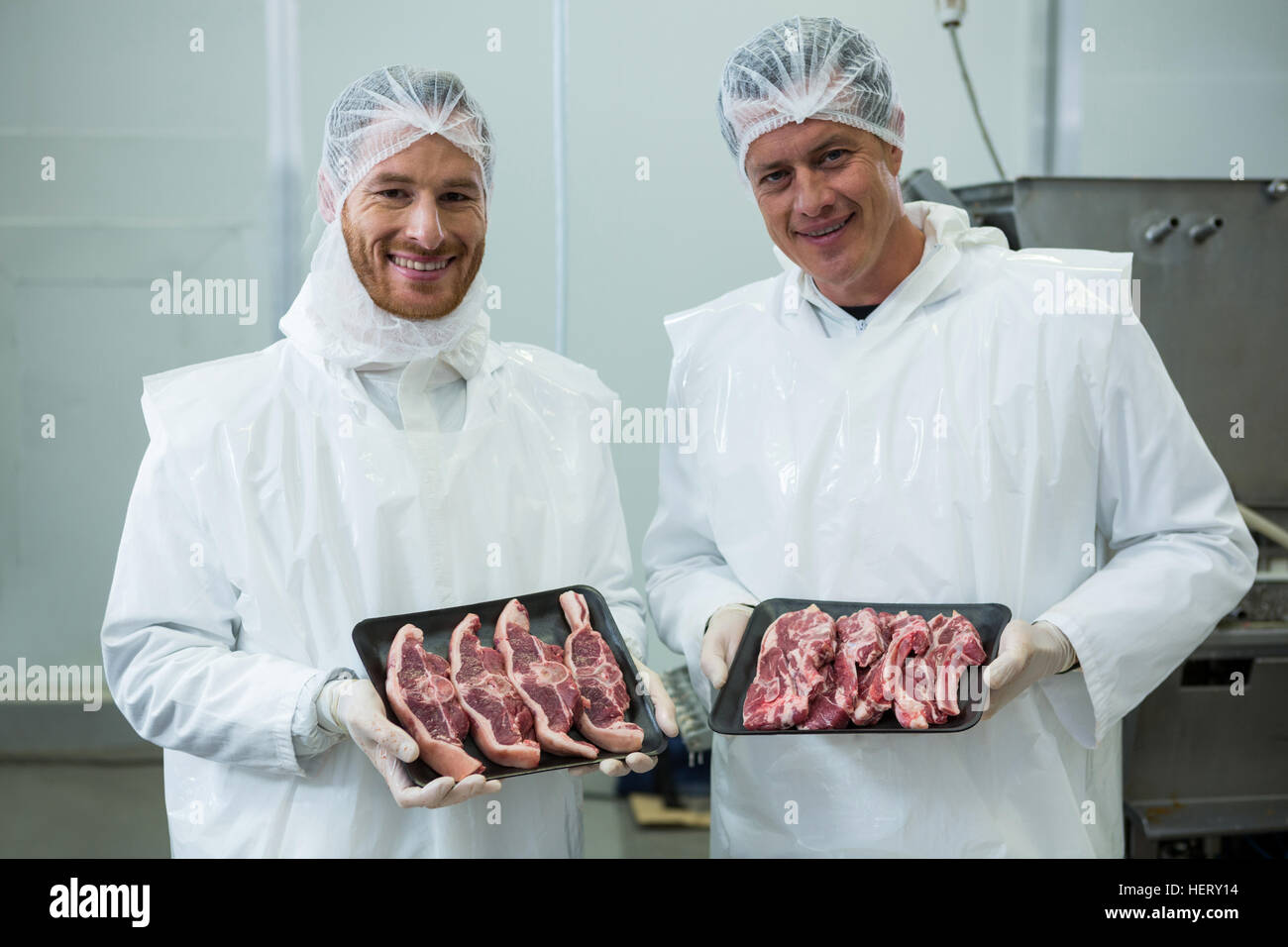 Portrait of butchers holding meat tray at meat factory Stock Photo Alamy