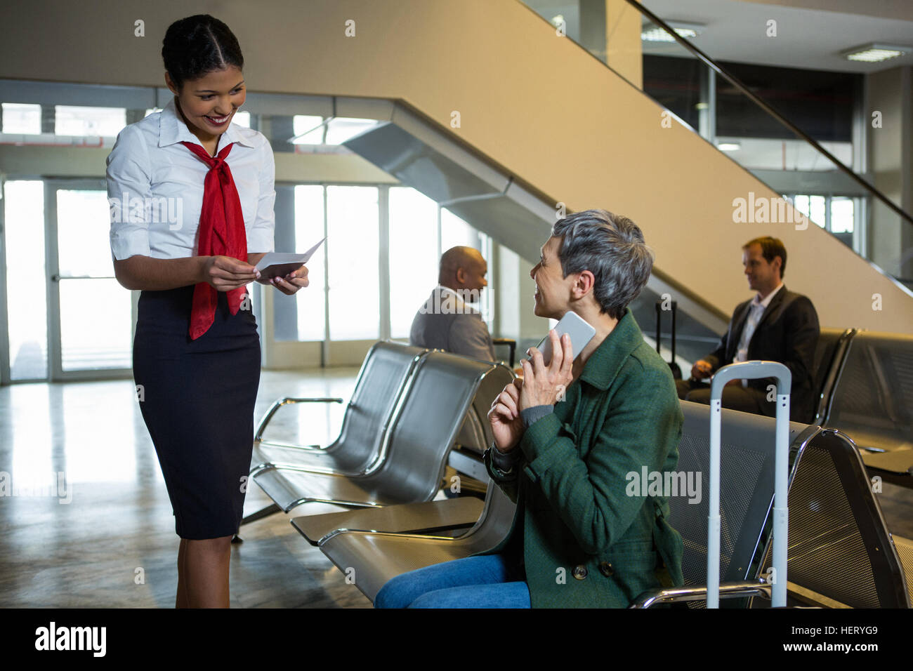 Airline check-in attendant checking passport at check-in waiting area at airport Stock Photo