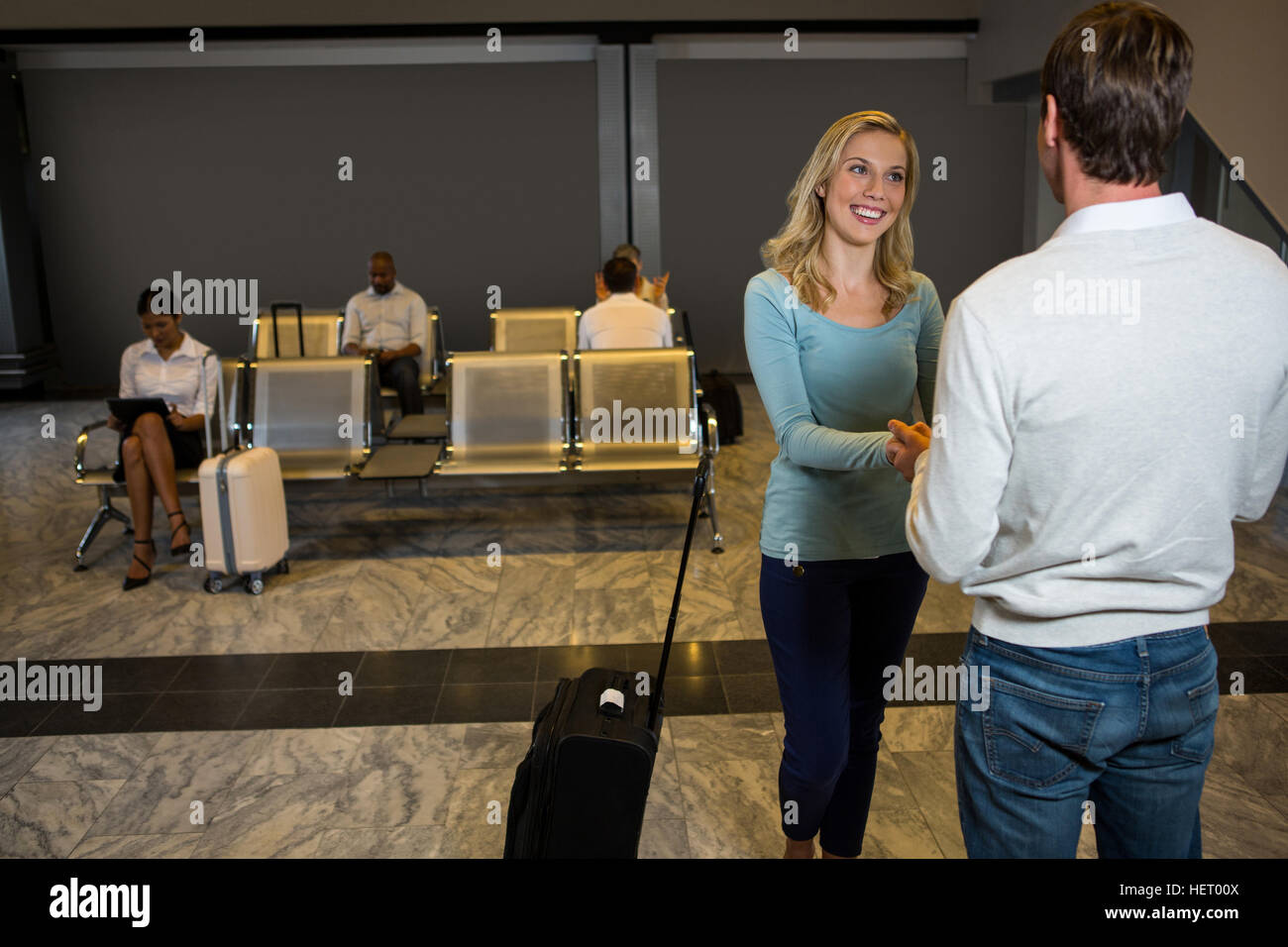 Happy couple holding hands while standing in waiting area at airport ...