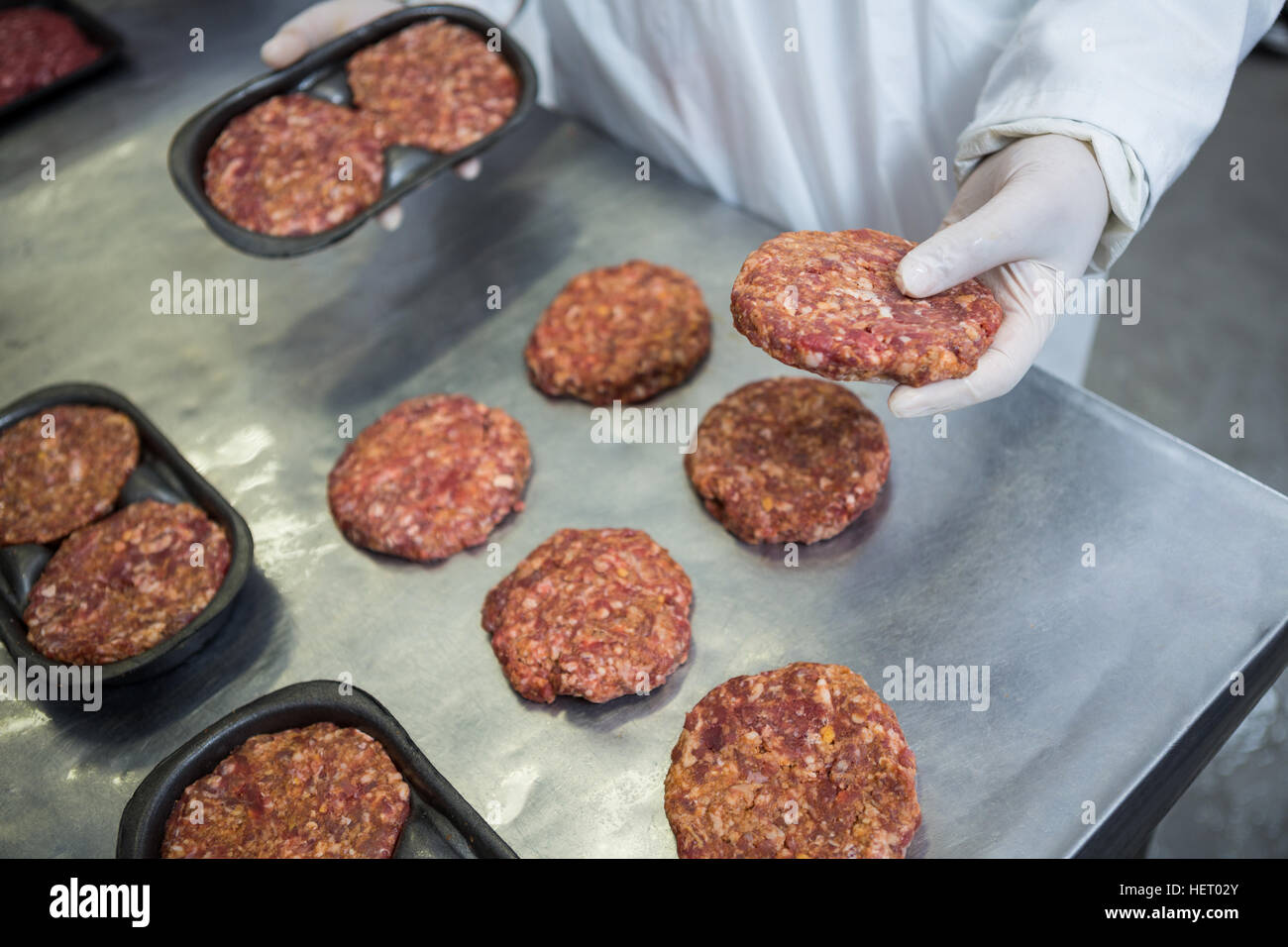 Closeup of butcher packaging hamburger patty at meat factory Stock