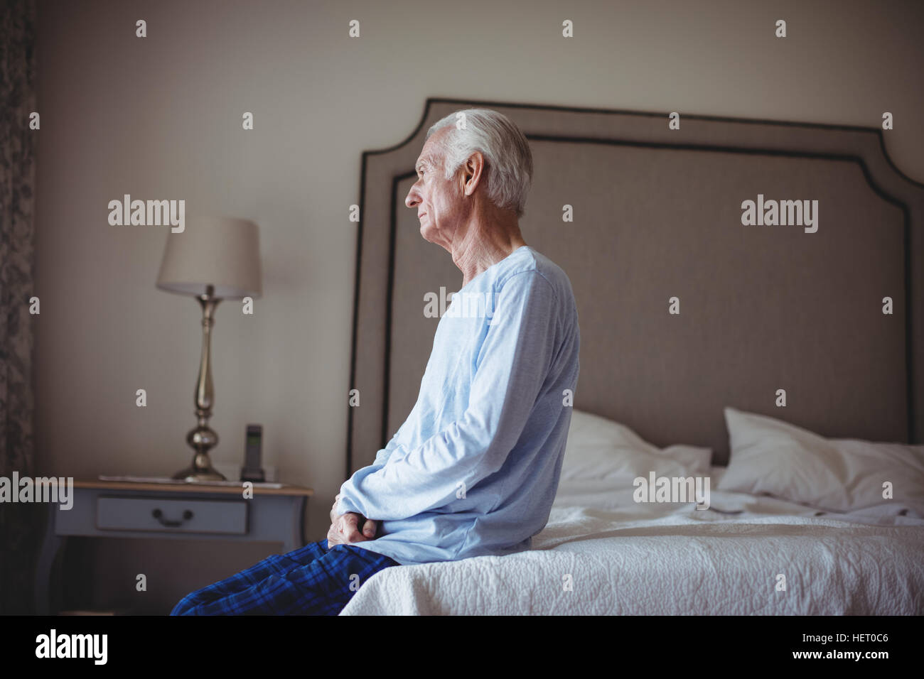 Thoughtful senior man sitting on bed in bedroom at home Stock Photo Alamy