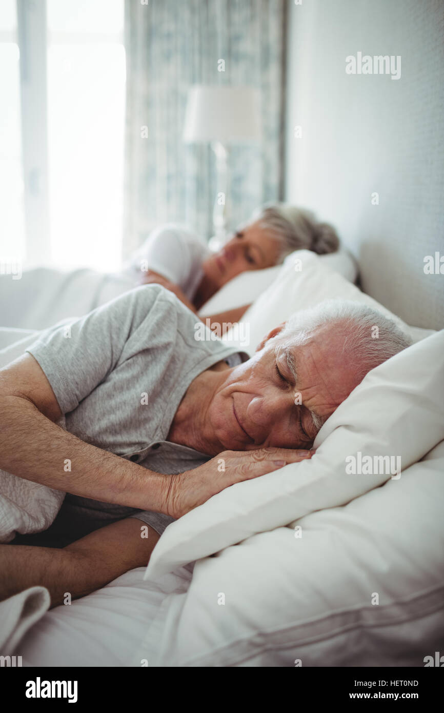 Senior couple sleeping on bed in bedroom Stock Photo - Alamy