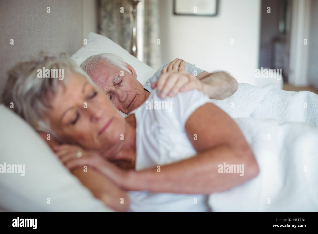 Senior couple sleeping on bed in bedroom Stock Photo - Alamy