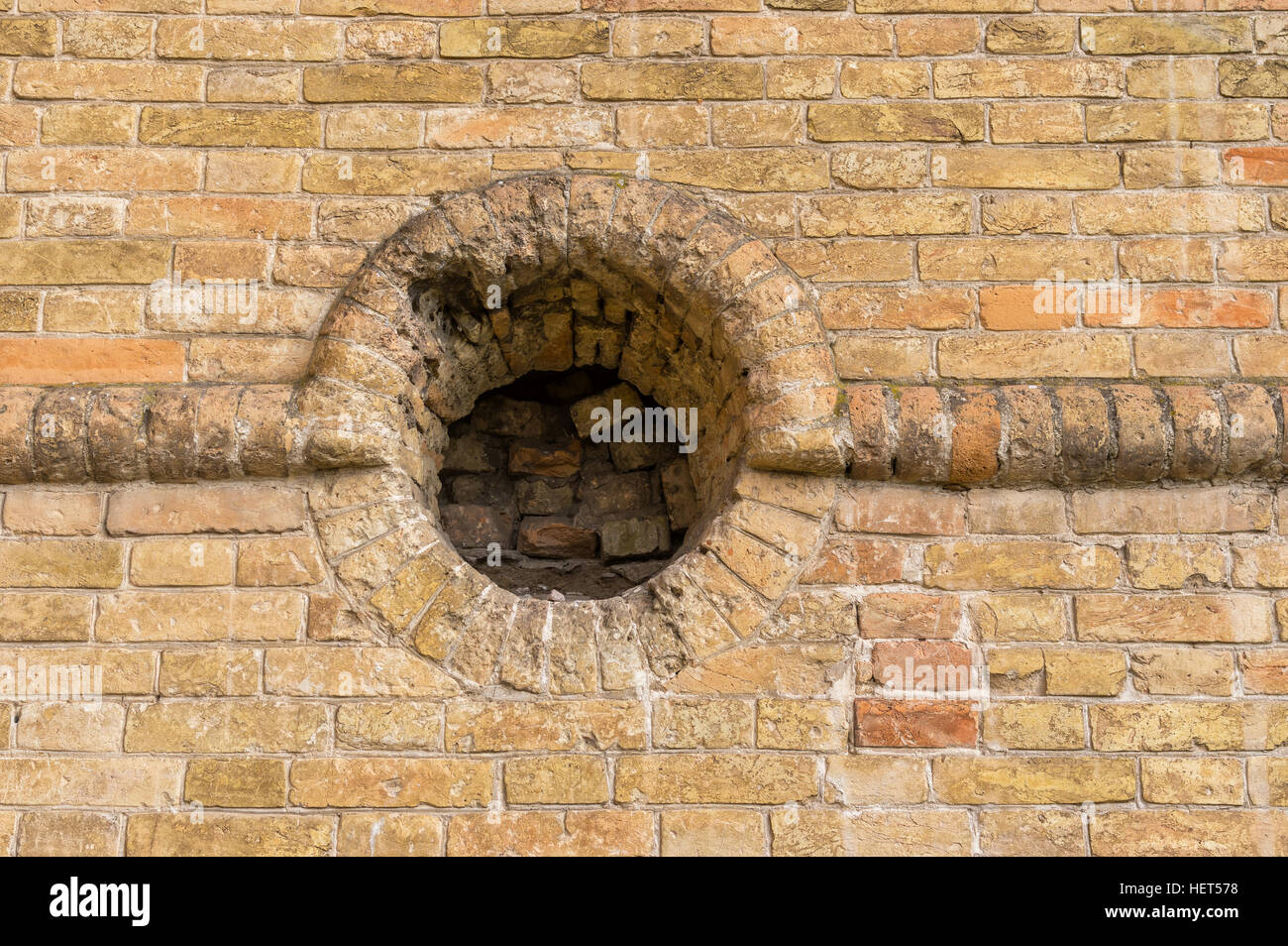 Ancient brick wall with round embrasure in Popov Castle located in town of Vasylivka, Ukraine Stock Photo