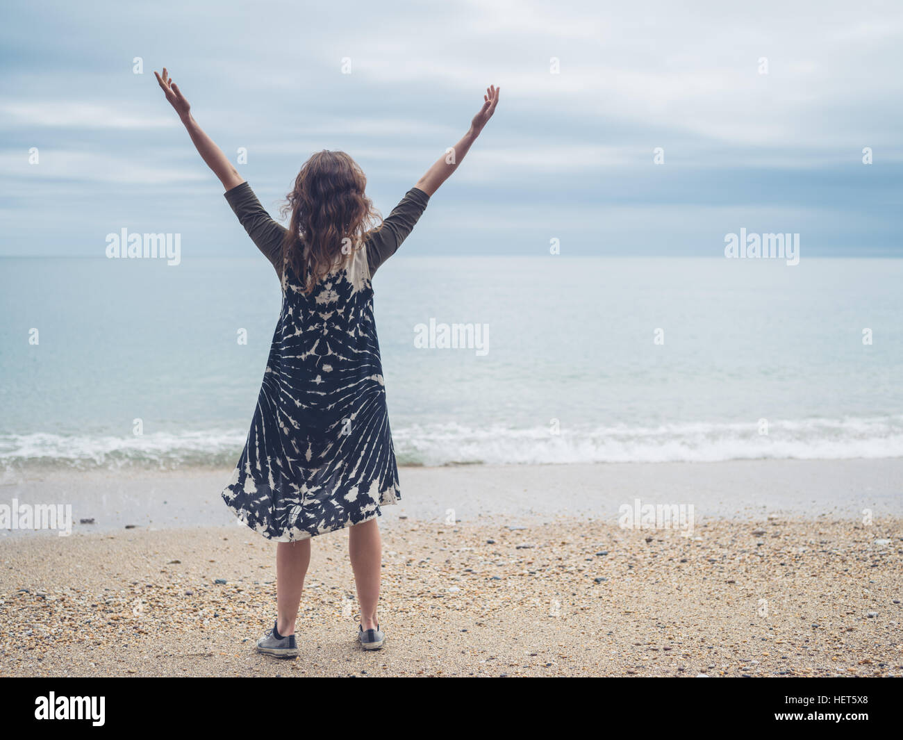 A young woman is raising her arms on the beach by the sea Stock Photo ...