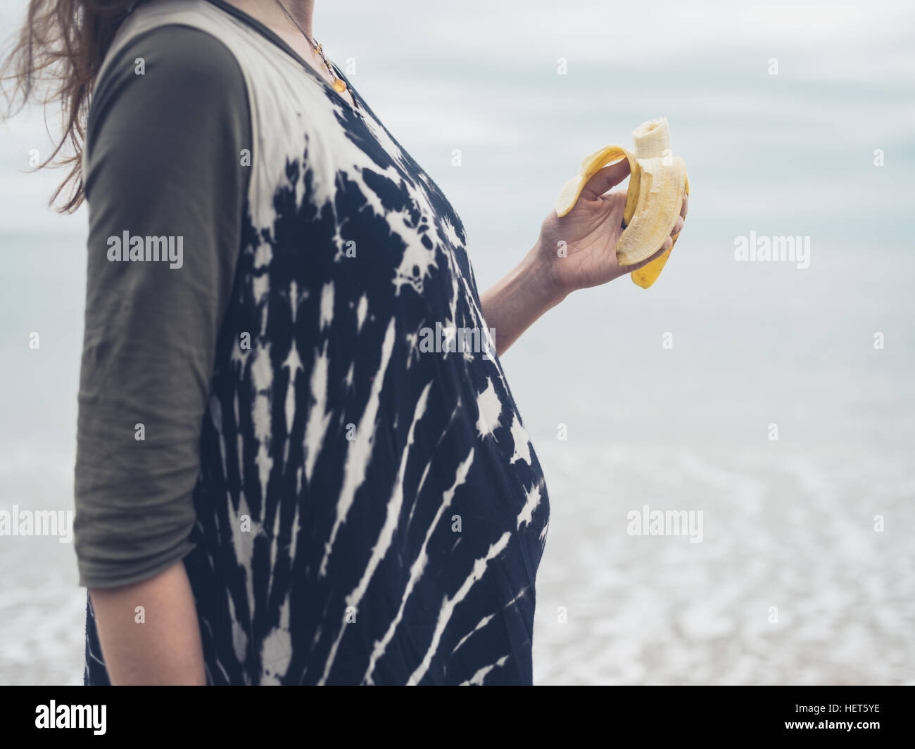 A pregnant woman is eating a banana on the beach Stock Photo Alamy
